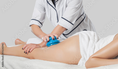 A masseur makes anti-cellulite massage on the legs, thighs, hips and buttocks with a vacuum massager in the spa. Overweight treatment, body sculpting.Cosmetology and massage concept.