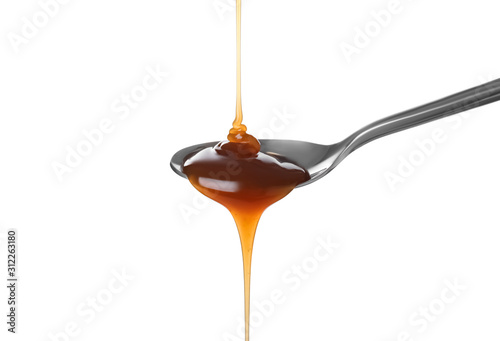 Pouring salted caramel into spoon isolated on white