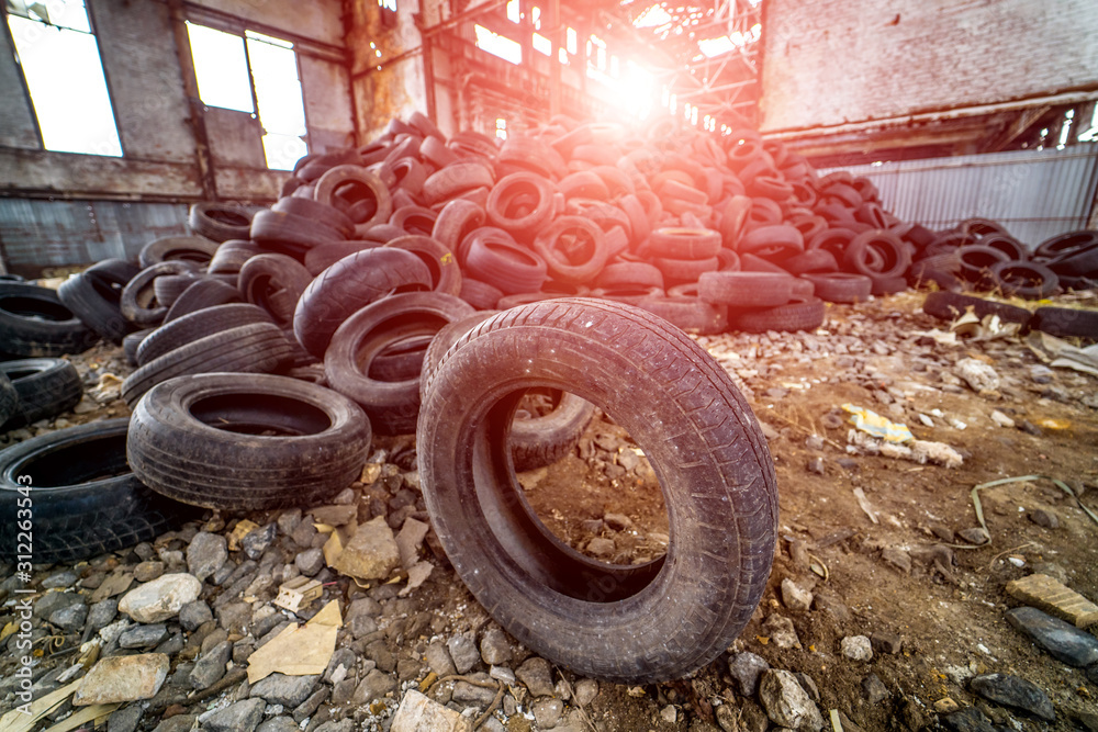 A pile of old rotten rubber tires on the ruined building background. Rustic factory.