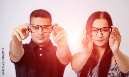 Portrait of a young couple looking through glasses isolated on white. Presenting spectacles