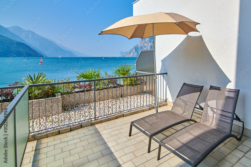 Deck chairs on the balcony, Lake Garda in summer, View of the beautiful Lake Garda from Torbole, surrounded by mountains