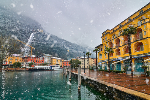 View of the beautiful Lake Garda surrounded by mountains,Riva del Garda town and Garda lake in the winter time on a snowy day,Trentino Alto Adige region