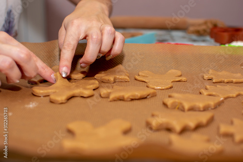 female hands spread the dough in the shape of a man on baking paper. The process of making Christmas cookies. Selective focus