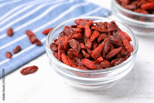 Dried goji berries on white wooden table, closeup