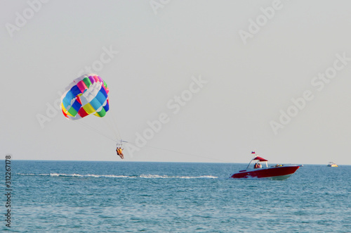 A bright multicolored parachute attached to the boat flies over the sea after the boat.