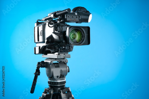 Modern professional video camera on blue background