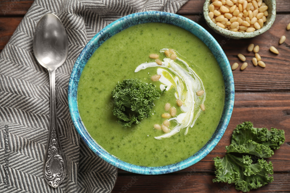 Tasty kale soup served on wooden table, flat lay Tasty kale soup served on wooden table, flat lay