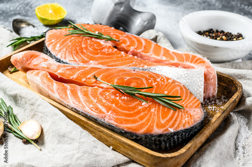 Fresh trout steak on a wooden tray with spices. Healthy seafood. Gray background. Top view
