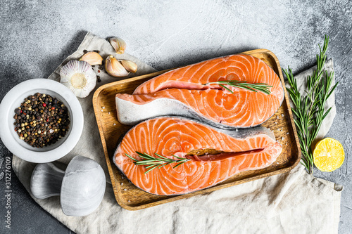 Fresh salmon steak on wooden tray with spices. Atlantic fish. Gray background. Top view