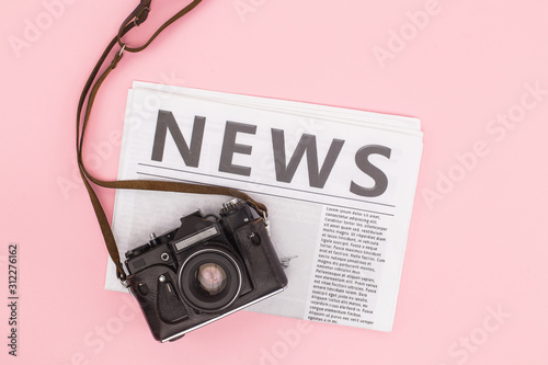 top view of film camera and newspaper isolated on pink with copy space