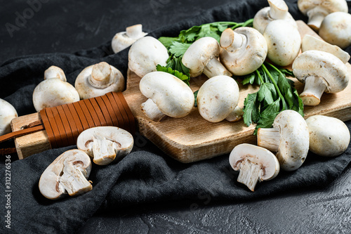Raw mushrooms champignon on a wooden cutting Board. Black background. Top view