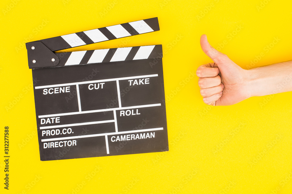 cropped view of man showing thumb up near clapperboard isolated on yellow