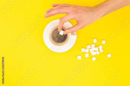 Принти на полотні cropped view of woman adding lump sugar to coffee isolated on yellow