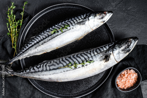 Raw mackerel fish with thyme and pink salt. Fresh seafood. Black background. Top view