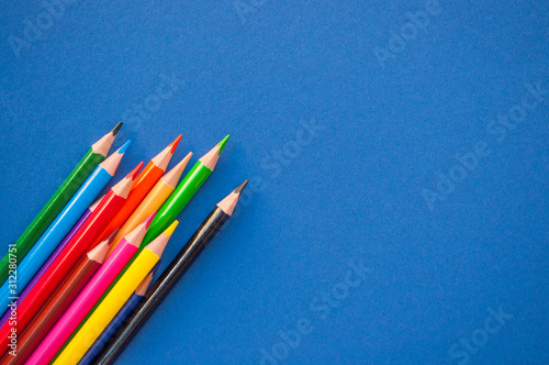 Colorful pencils on blue background with copyspace. 2020 color trend.