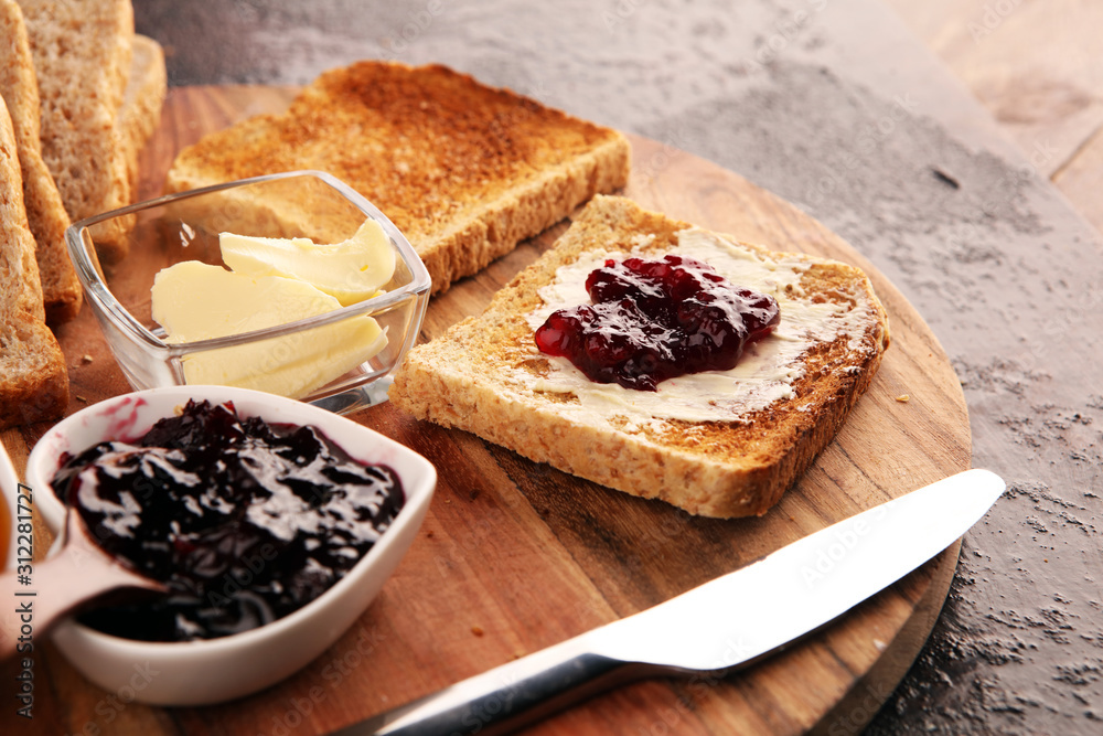 Toast bread with homemade strawberry jam and apricot marmalade on rustic table served with butter for breakfast or brunch on table - obrazy, fototapety, plakaty 