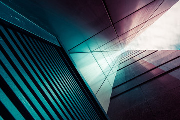 Abstract background. View through modern high rising skyscraper chimney upwards to blue sky with white clouds - abstract architecture detail background in turquoise teal blue to burgundy purple colors