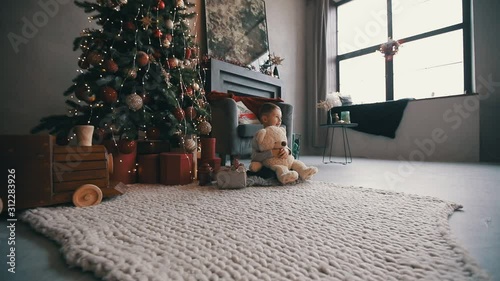 happy kid with teddy bear sitting near the xmas tree
