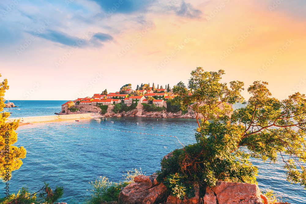Picturesque summer view to the Sveti Stefan island, dramatic sunset sky, luxury resort on the Adriatic sea coast in Montenegro