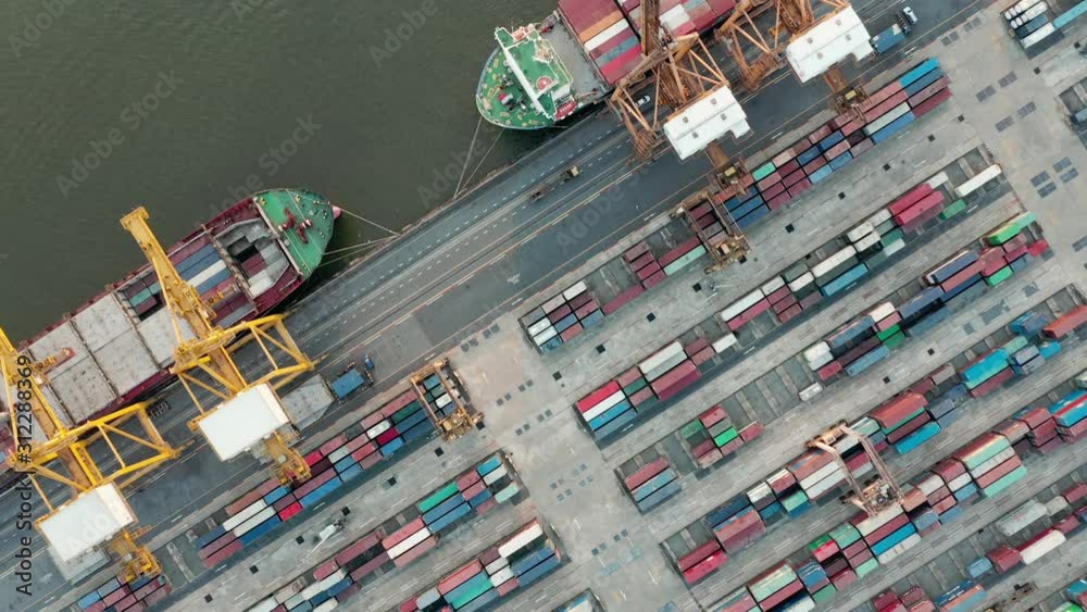 Aerial view over industrial import or export port of Thailand in Bangkok with many rows and stacks of container and big container loader ship vessel.
