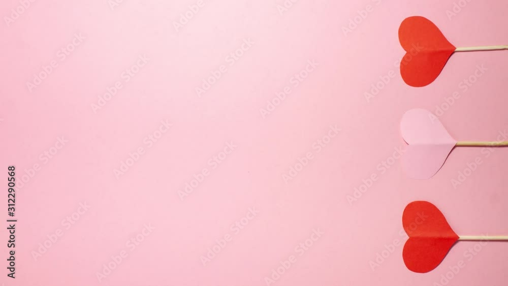 Red and pink hearts on pink background at the right side. Valentines day concept. Flat lay top view stop motion animation with copy space