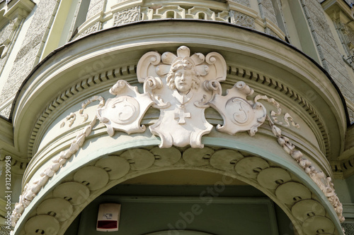 Plaster male head figure in barroque style entrance way, with round portico in Ljubljana
