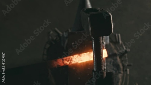 Forge workshop. Smithy manual production. Hands of smith with hammer hit on glowing hot metal, on the anvil, the forging process. Blacksmith makes iron products for manufacture of fireplace, stove.