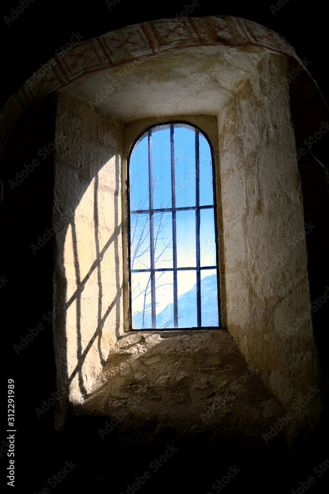 A window in a mountain chapel during winter
