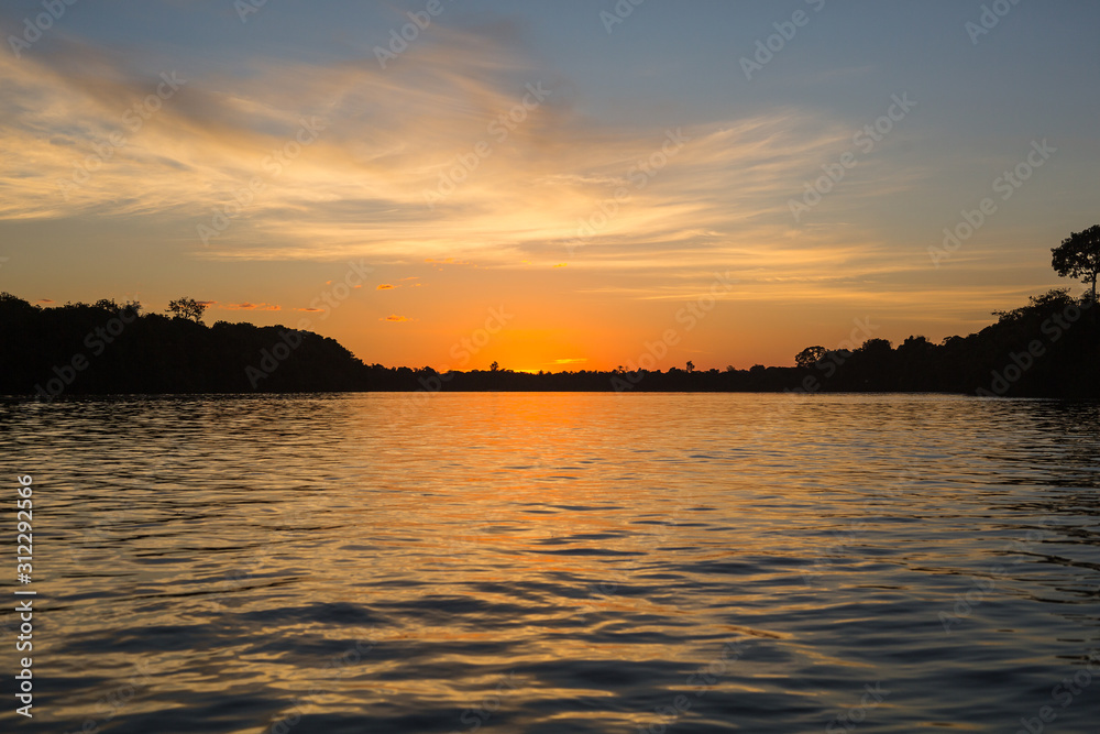 A golden sunset over a river in the Amazon rainforest.