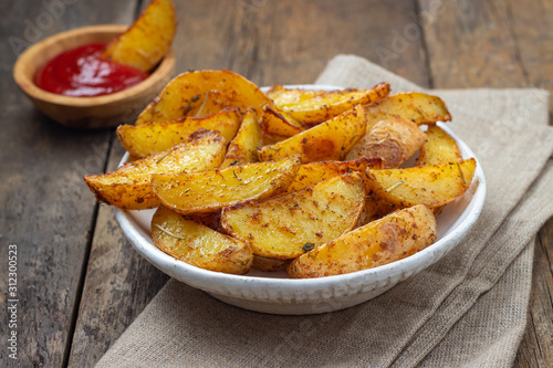Canvas Print Baked potato with spices, herbs and ketchup in a plate on the wooden table