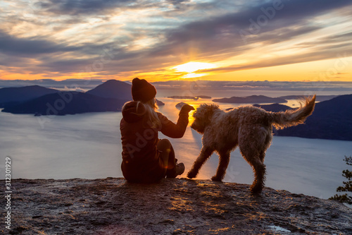 Adventurous Girl Hiking on top of a Mountain with a dog during a colorful sunset. Taken on Tunnel Bluffs Hike, near Vancouver and Squamish, British Columbia, Canada. © edb3_16