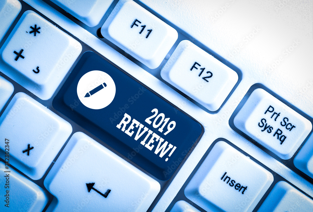 Conceptual hand writing showing 2019 Review. Concept meaning remembering past year events main actions or good shows White pc keyboard with note paper above the white background Conceptual hand writing showing 2019 Review. Concept meaning remembering past year events main actions or good shows White pc keyboard with note paper above the white background