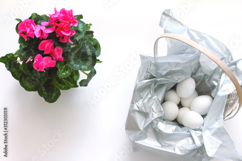 basket with eggs and cyclamen flower. minimalistic composition for Easter. flat lay