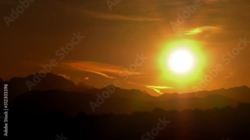 Timelapse sun setting over silhouette of mountains