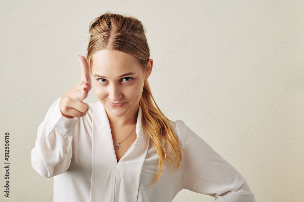 Smiling young business lady making hand gun gesture and looking at camera Smiling young business lady making hand gun gesture and looking at camera