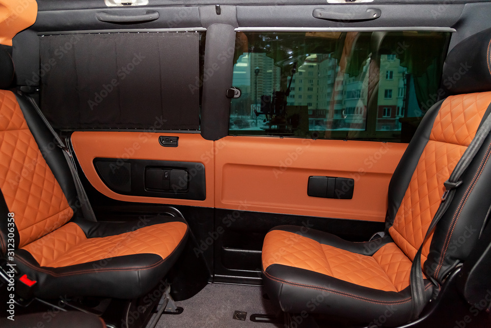Four rear seats in a minibus are deployed to each other and tightened in black and brown leather with a diamond-shaped stitching thread in a workshop for tuning and repairing vehicles. Van car. Four rear seats in a minibus are deployed to each other and tightened in black and brown leather with a diamond-shaped stitching thread in a workshop for tuning and repairing vehicles. Van car.