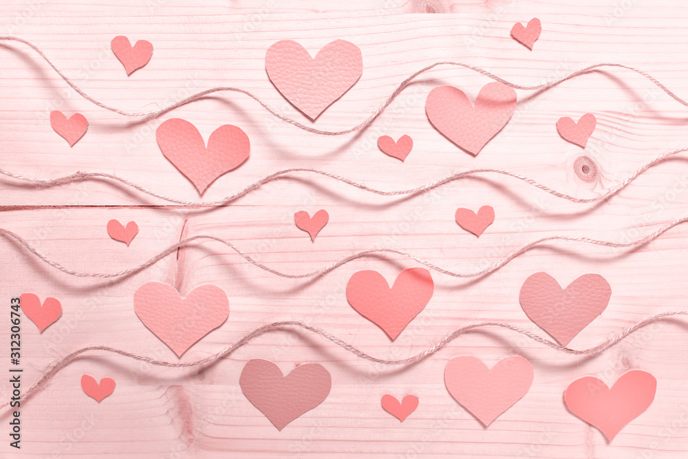 Valentine day pattern with hearts arranged on wooden background with wavy rope tinted with pink color.