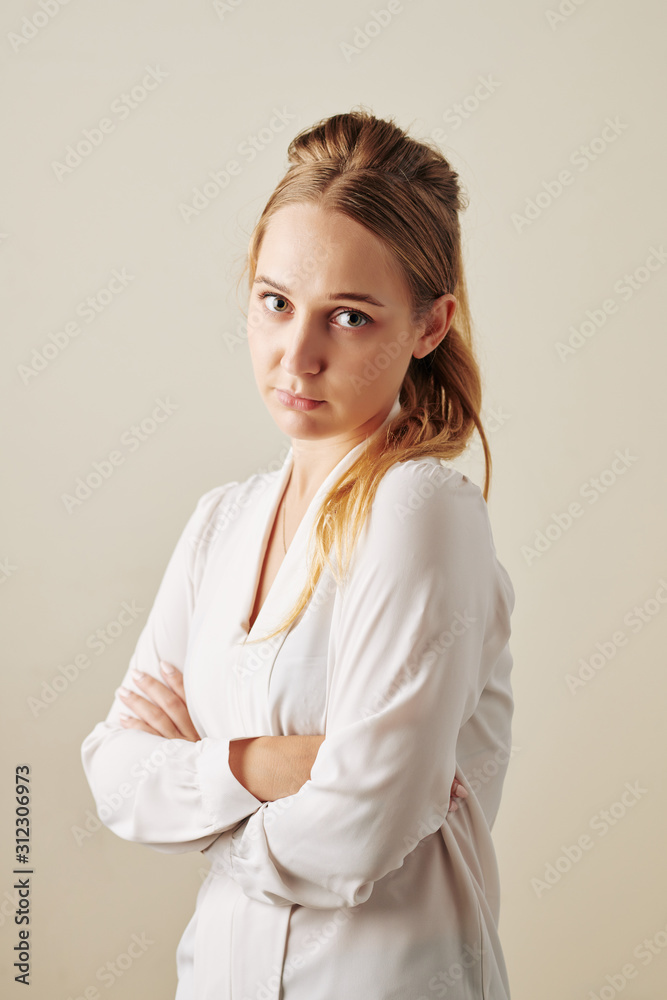 Studio portrait of offended young woman folding arms and looking at camera Studio portrait of offended young woman folding arms and looking at camera