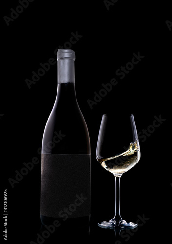 A bottle of precious white wine along with a glass. The wine in the glass moves and creates a dynamic effect.