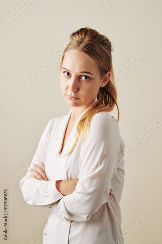 Studio portrait of offended young woman folding arms and looking at camera