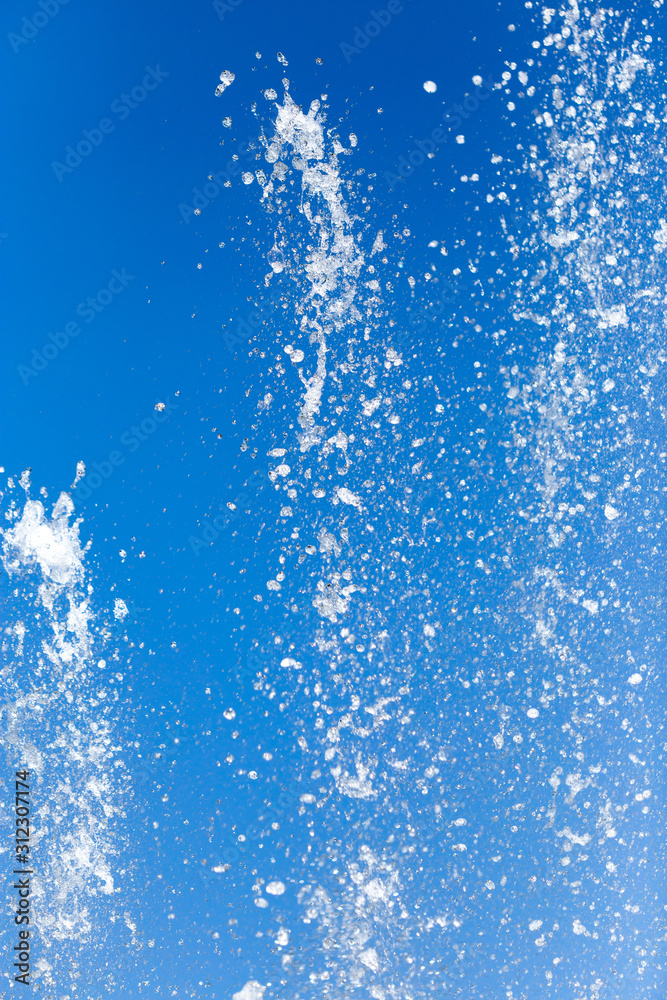 Splashing water from a fountain on a background of blue sky Splashing water from a fountain on a background of blue sky
