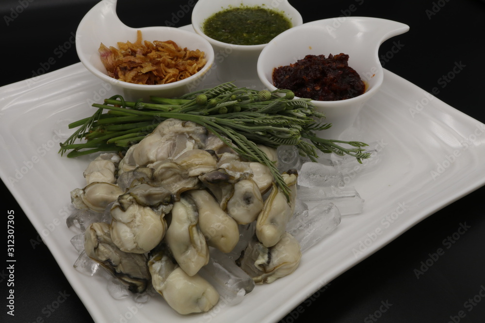 Fresh oyster with seafood sauce, chili paste and acacia on white plate