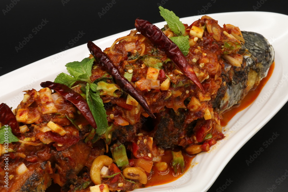 Thai spicy fried fish with herbs and chili on white plate