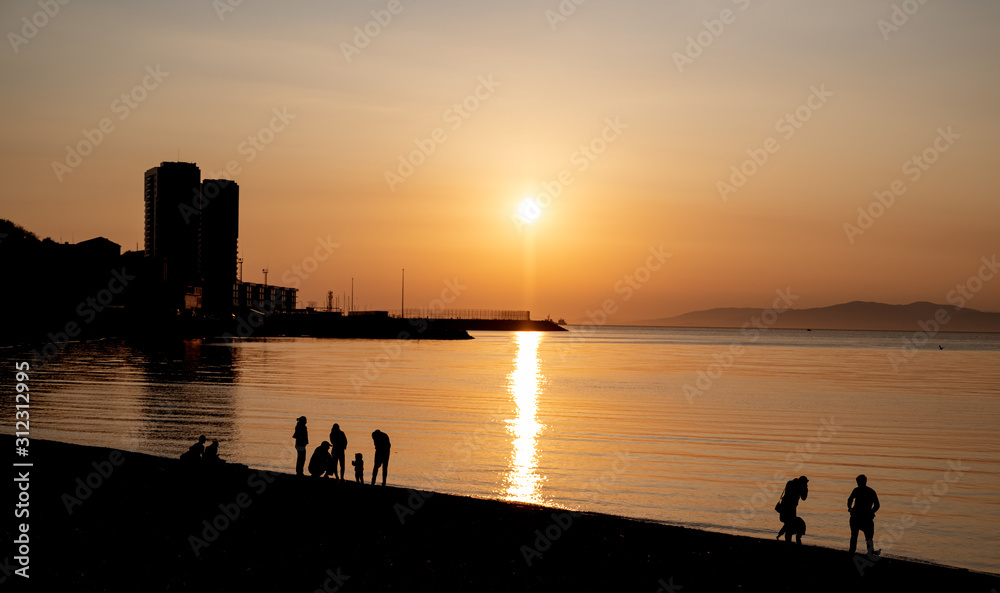 Silhouettes of people at sunset on the sea.