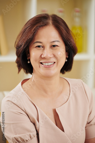 Portrait of happy pretty middle-aged Vietnamese woman smiling at camera