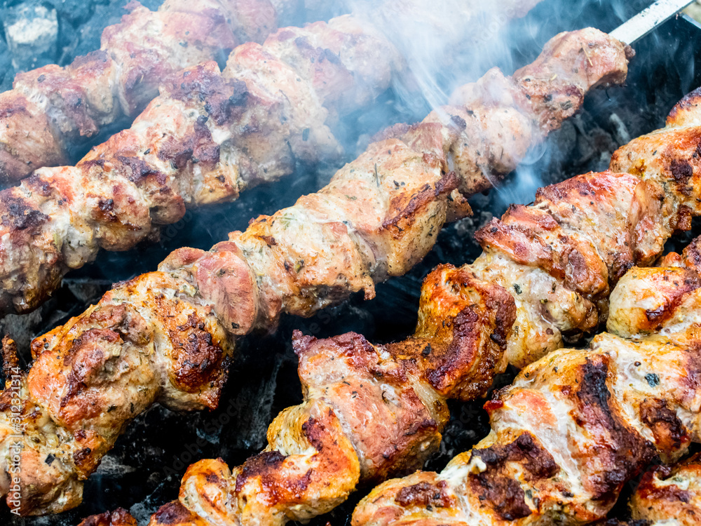 Frying pork on a skewer over a brazier. Turning meat over coals. Appetizing shish kebab.