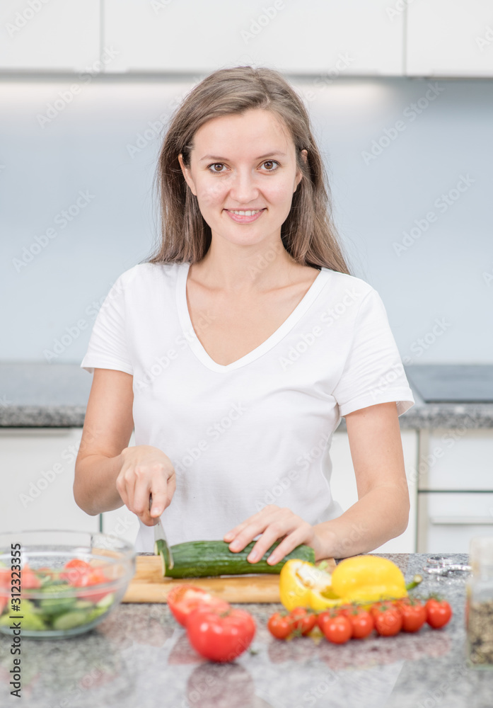 Smiling young woman cooking in the kitchen at home