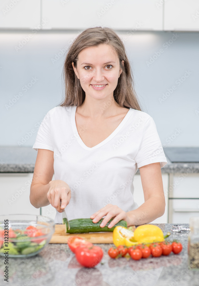 Smiling young woman cooking in the kitchen at home Smiling young woman cooking in the kitchen at home