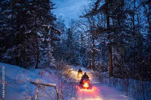 snowmobile in the evening goes through the winter forest. headlights. night road through the winter forest. snowmobile at night