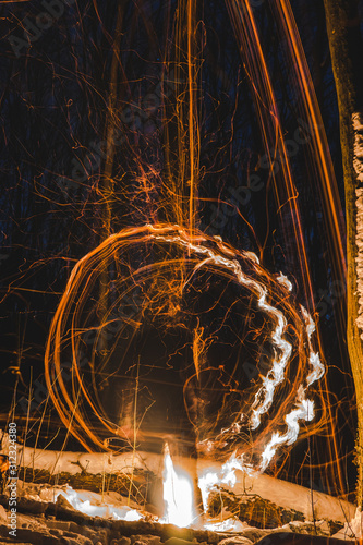 burning bonfire with soft glowing flame and sparkles flying all around. relaxing and enjoying the atmosphere, long exposure, figures from fire, fire ring, hiking travel concept, vertical photo photo